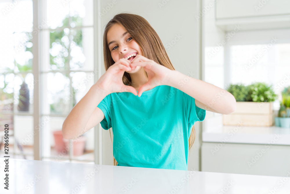 Beautiful young girl kid wearing green t-shirt smiling in love showing heart symbol and shape with hands. Romantic concept. Beautiful young girl kid wearing green t-shirt smiling in love showing heart symbol and shape with hands. Romantic concept.