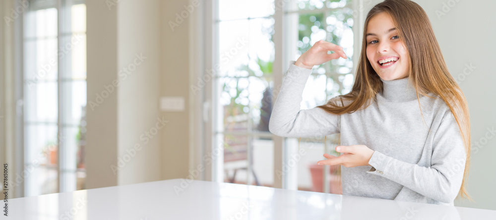 Wide angle picture of beautiful young girl kid wearing casual sweater gesturing with hands showing big and large size sign, measure symbol. Smiling looking at the camera. Measuring concept.