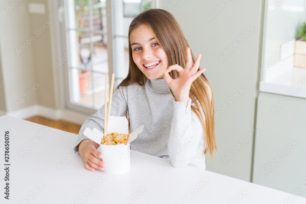 Beautiful young girl kid eating asian rice in delivery box doing ok sign with fingers, excellent symbol Beautiful young girl kid eating asian rice in delivery box doing ok sign with fingers, excellent symbol