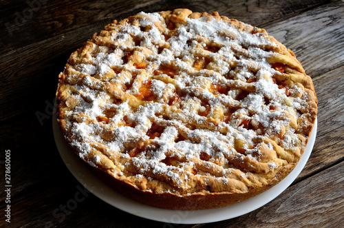 Homemade apricot pie in a white plate on a wooden table.