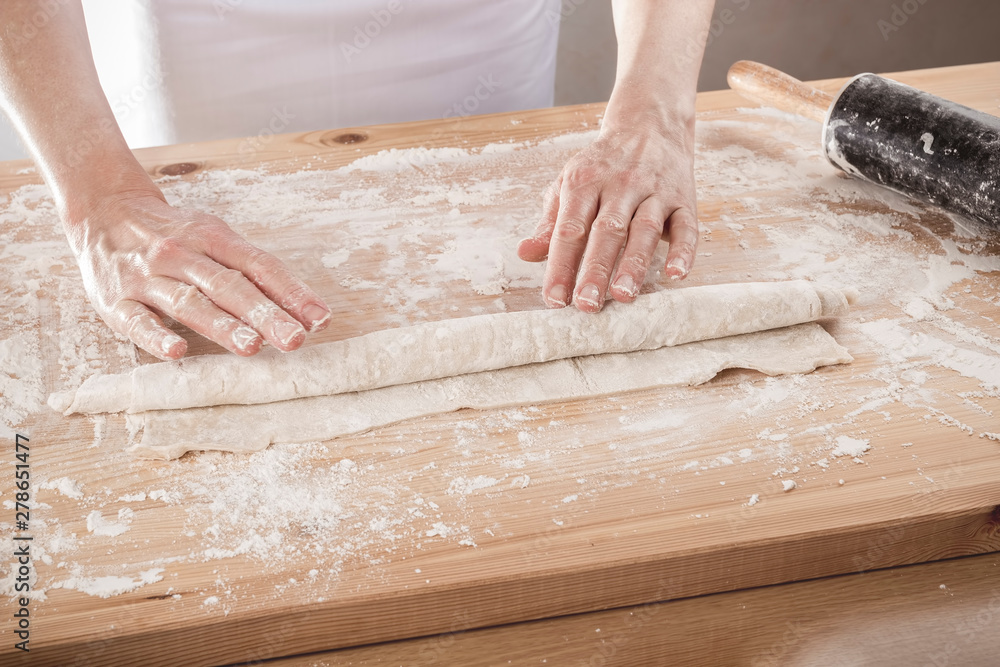Woman rolling dough on a wooden rustic table