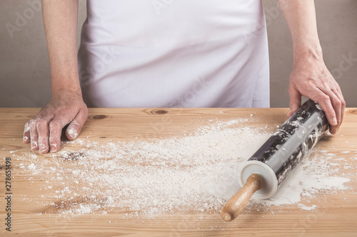 Woman with rolling pin and flour on a wooden rustic table