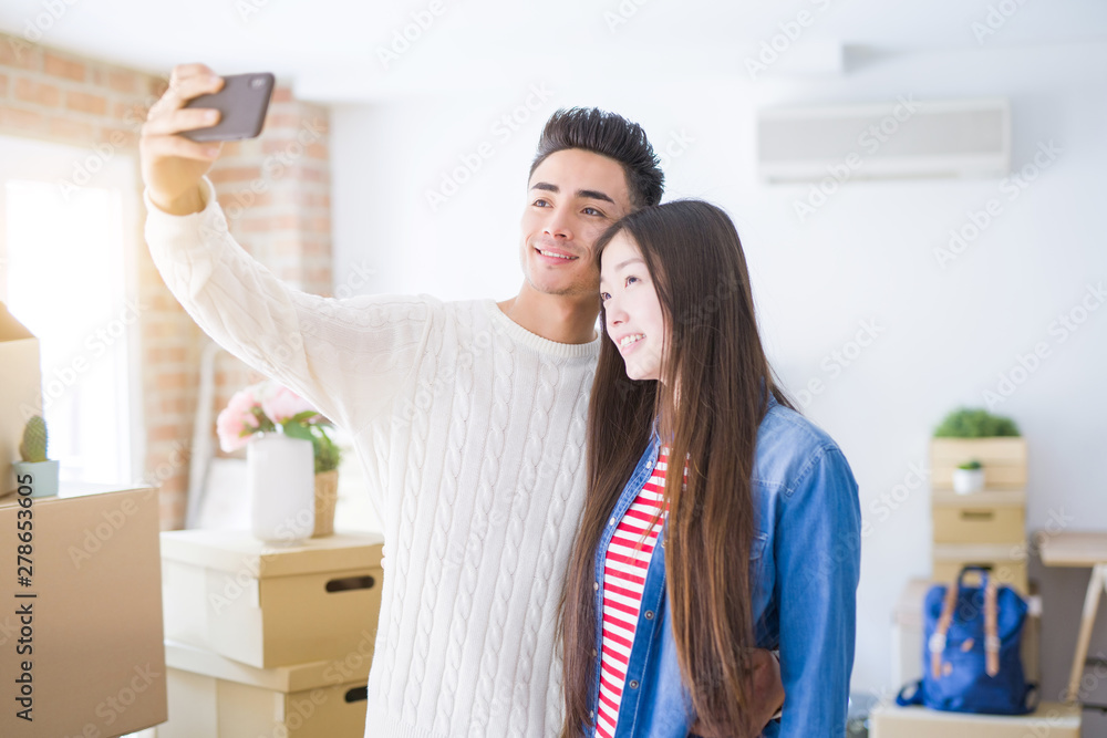 Young asian couple smiling taking a selfie photo with smartphone, moving to a new home together Young asian couple smiling taking a selfie photo with smartphone, moving to a new home together