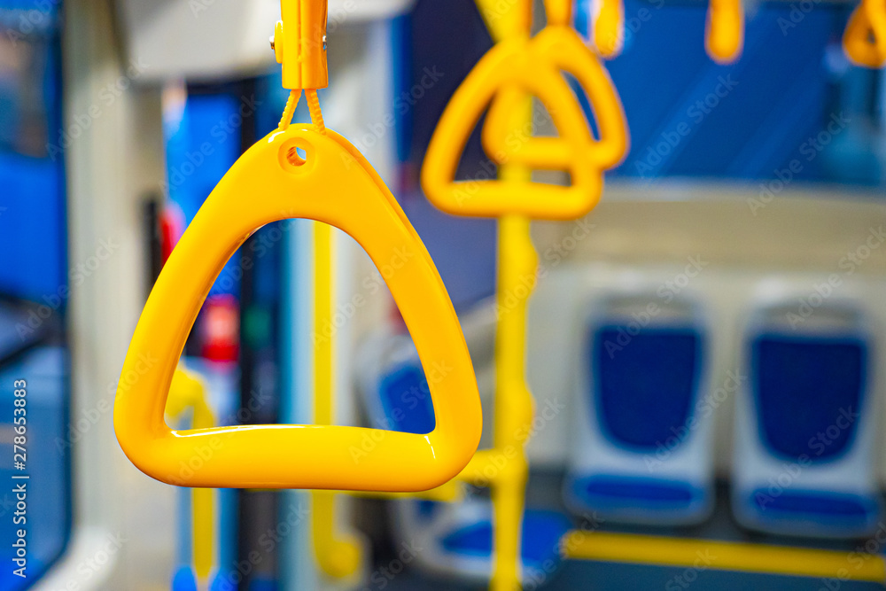Passenger transport interior. Triangular plastic handles for passengers. Hanging transport handrail. Safety equipment of the bus cabin. Hold on to the handrail to avoid falling passengers. Passenger transport interior. Triangular plastic handles for passengers. Hanging transport handrail. Safety equipment of the bus cabin. Hold on to the handrail to avoid falling passengers.