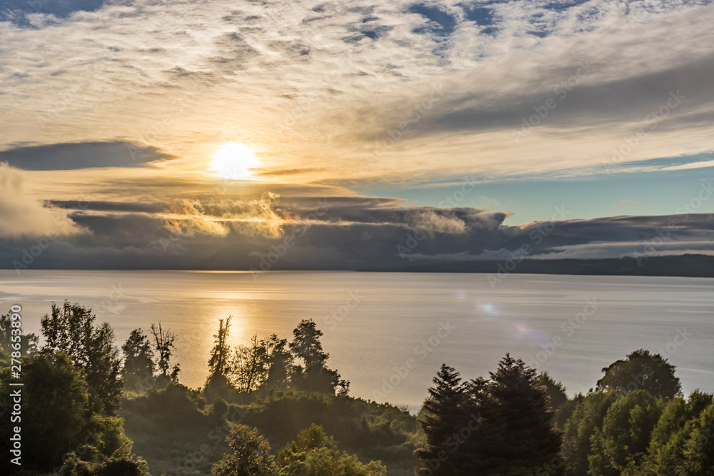A dramatical sky view in between the clouds over Rupanco Lake, one of the Great lakes in Southern Chile during sunrise an amazing volcanic landscape with the lake and the forests, Chile
