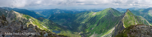 Panoramic view from Rohac peak on Western Tatra mountains or Rohace panorama. Sharp green mountains - ostry rohac, placlive and volovec with hiking trail on ridge. Summer blue sky white clouds.