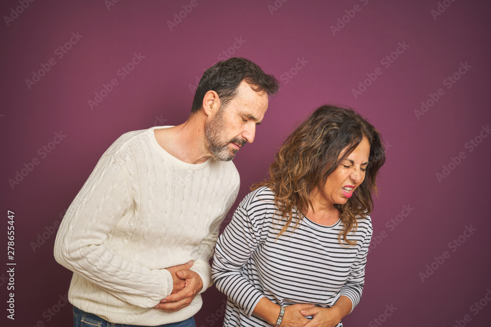Naklejka premium Beautiful middle age couple wearing winter sweater over isolated purple background with hand on stomach because nausea, painful disease feeling unwell. Ache concept.