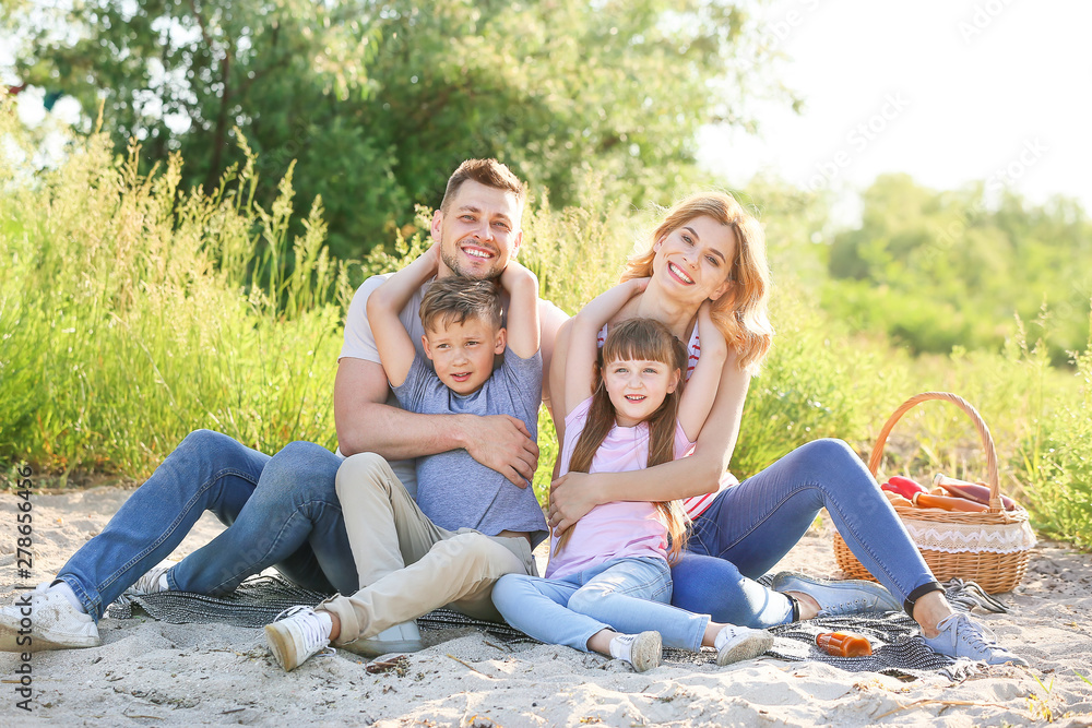 Happy family on summer picnic near river Happy family on summer picnic near river