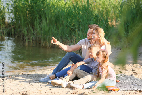 Happy family on summer picnic near river