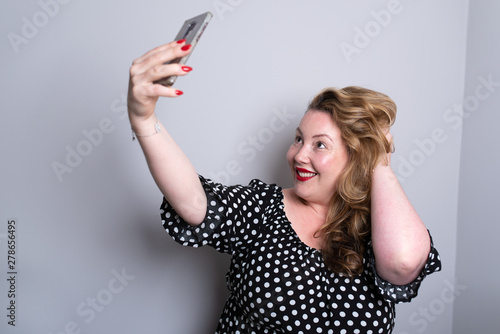 Cuadro en lienzo Beautiful overweight plus size model taking selfies for social media with her smart phone