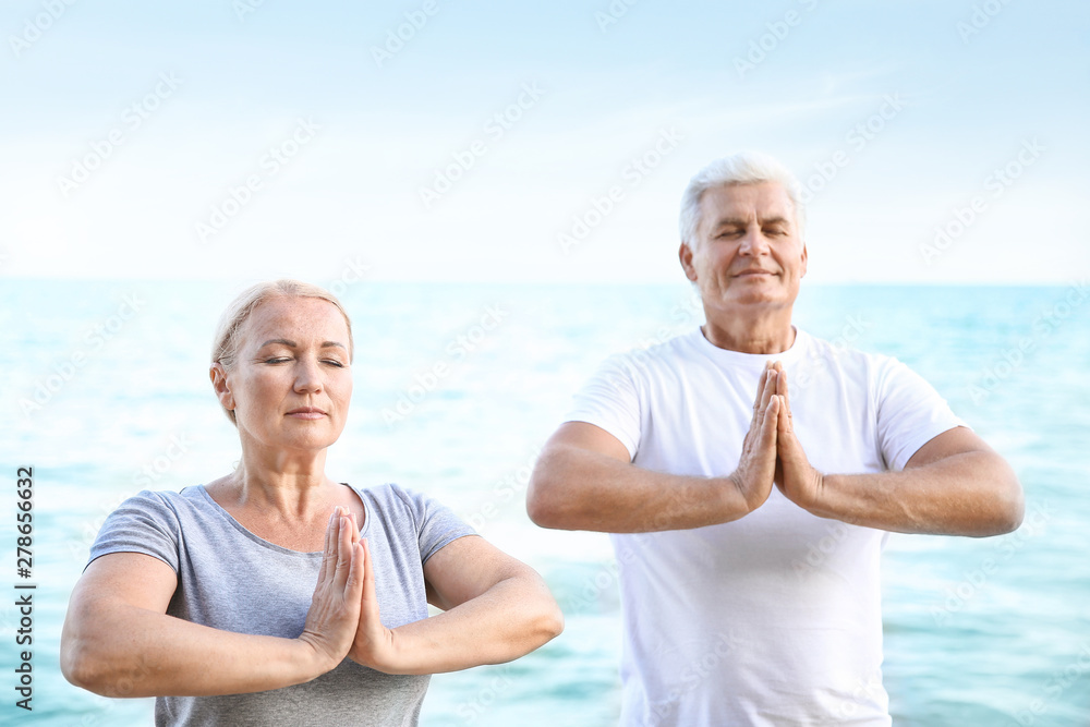 Mature couple practicing yoga at sea resort Mature couple practicing yoga at sea resort