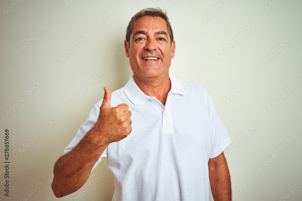 Handsome middle age man wearing polo standing over isolated white background doing happy thumbs up gesture with hand. Approving expression looking at the camera with showing success. Handsome middle age man wearing polo standing over isolated white background doing happy thumbs up gesture with hand. Approving expression looking at the camera with showing success.
