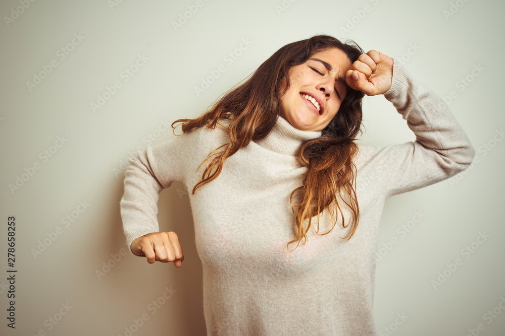 Fototapeta premium Young beautiful woman wearing winter sweater standing over white isolated background stretching back, tired and relaxed, sleepy and yawning for early morning