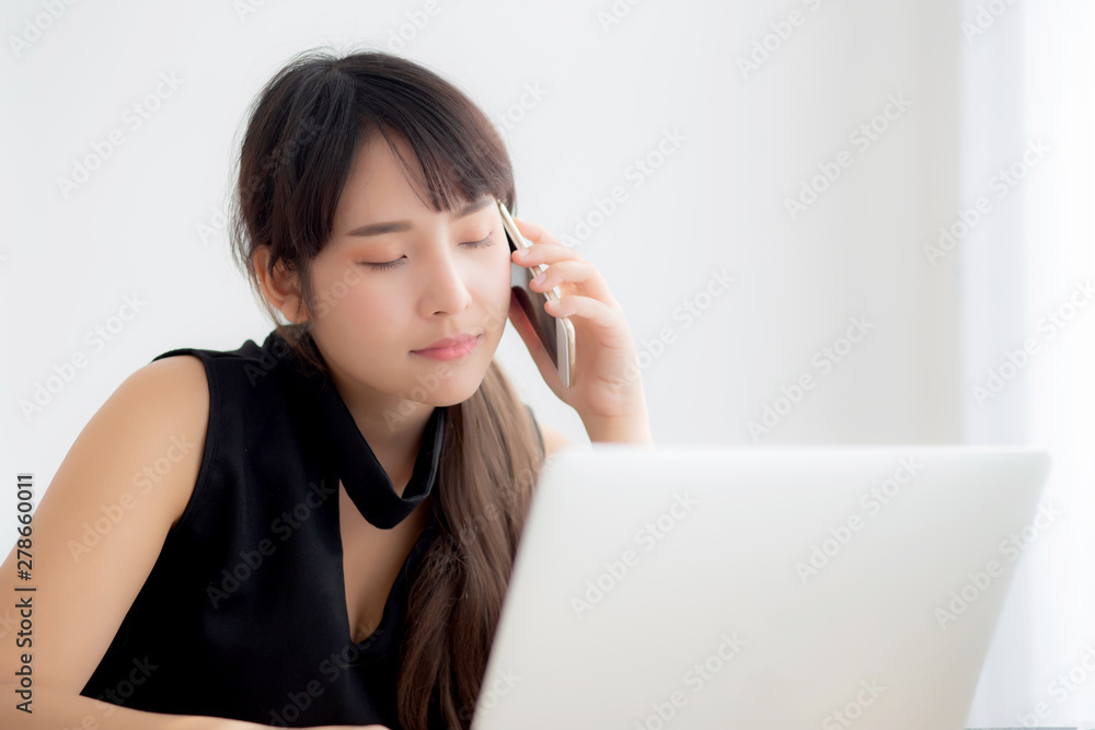 Beautiful young freelance asian woman smiling working on laptop computer and talking mobile smart phone at desk office with professional, girl using notebook, business and lifestyle concept. Beautiful young freelance asian woman smiling working on laptop computer and talking mobile smart phone at desk office with professional, girl using notebook, business and lifestyle concept.