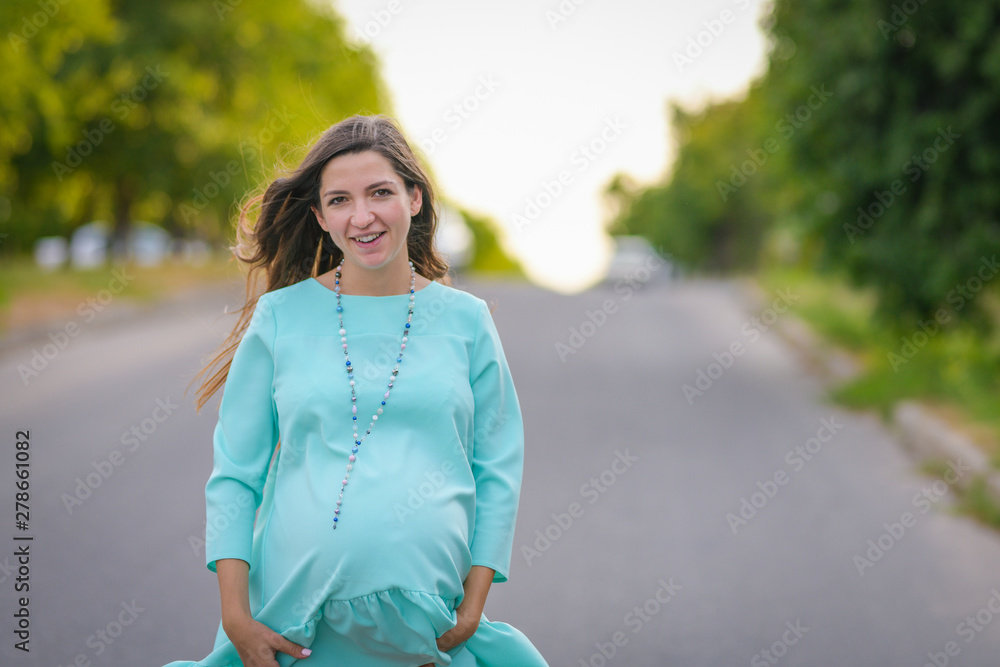 Pregnant girl hugs her pregnant belly. Happy pregnant woman is embracing belly on nature, outdoors Pregnant girl hugs her pregnant belly. Happy pregnant woman is embracing belly on nature, outdoors