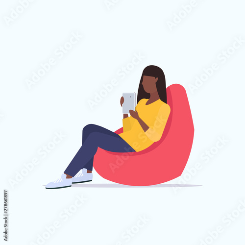 woman sitting in bean bag armchair african american girl freelancer or office worker using digital tablet social media communication concept flat full length