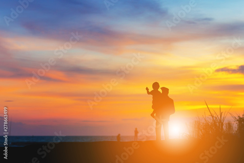 Silhouette of Grandfather and grandchild looking sun down and walking on the beach evening sunset background, Happy family concept