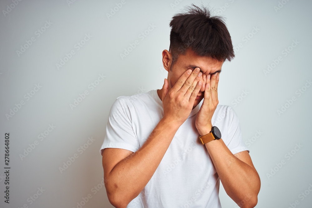 Young asian chinese man wearing t-shirt standing over isolated white background rubbing eyes for fatigue and headache, sleepy and tired expression. Vision problem Young asian chinese man wearing t-shirt standing over isolated white background rubbing eyes for fatigue and headache, sleepy and tired expression. Vision problem