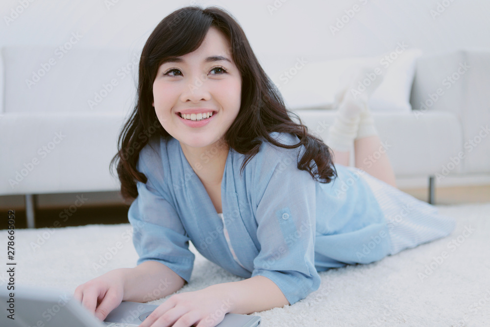 寝転んでノートパソコンを操作する女性 寝転んでノートパソコンを操作する女性