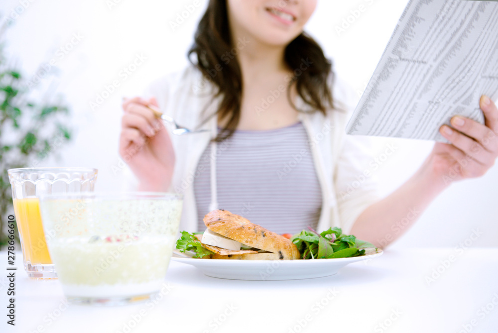 朝食と新聞を読む女性