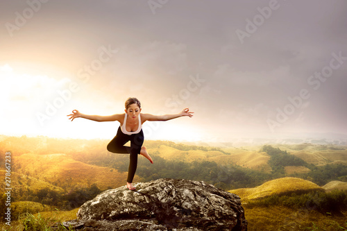 Asian healthy woman practicing yoga on the rock
