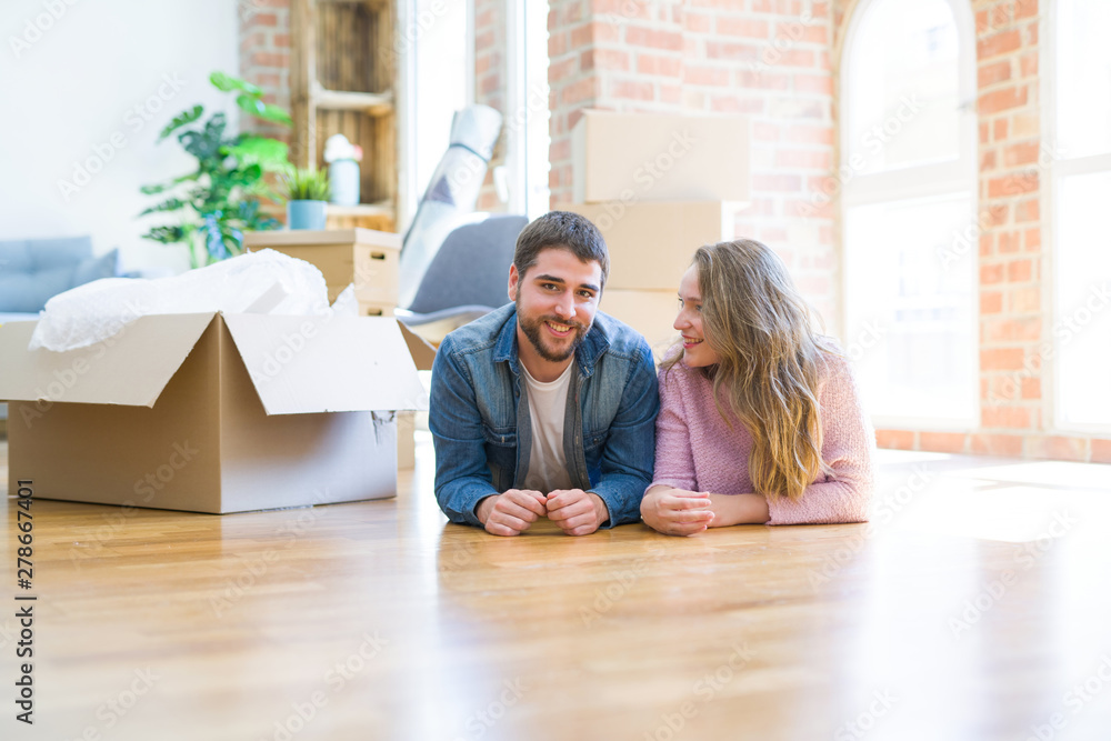 Young beautiful couple in love relaxing lying on the floor together with cardboard boxes around for moving to a new house Young beautiful couple in love relaxing lying on the floor together with cardboard boxes around for moving to a new house