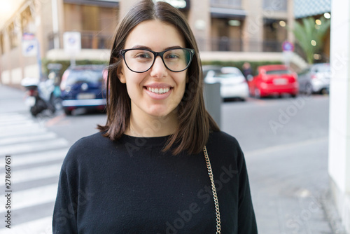 Fotografie Beautiful young brunette woman smiling excited walking down the city streets, ha