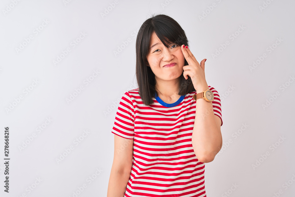Young beautiful chinese woman wearing red striped t-shirt over isolated white background Shooting and killing oneself pointing hand and fingers to head like gun, suicide gesture. Young beautiful chinese woman wearing red striped t-shirt over isolated white background Shooting and killing oneself pointing hand and fingers to head like gun, suicide gesture.