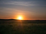 Sunset in the Kazakh steppe. Spacious steppes surrounded by low mountains. Beautiful view of horizon.