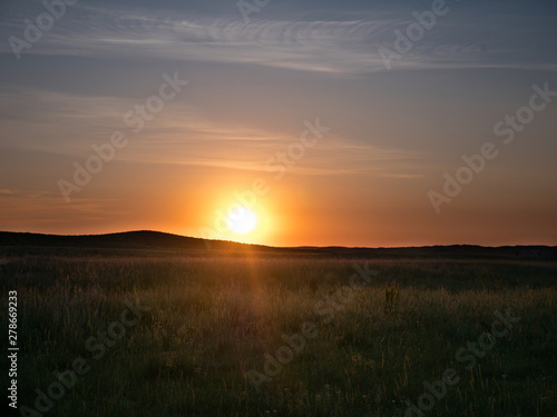 Sunset in the Kazakh steppe. Spacious steppes surrounded by low mountains. Beautiful view of horizon.