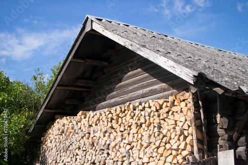 split wood for the fireplace, stacked in a pile near the old house. alternative, renewable energy source.