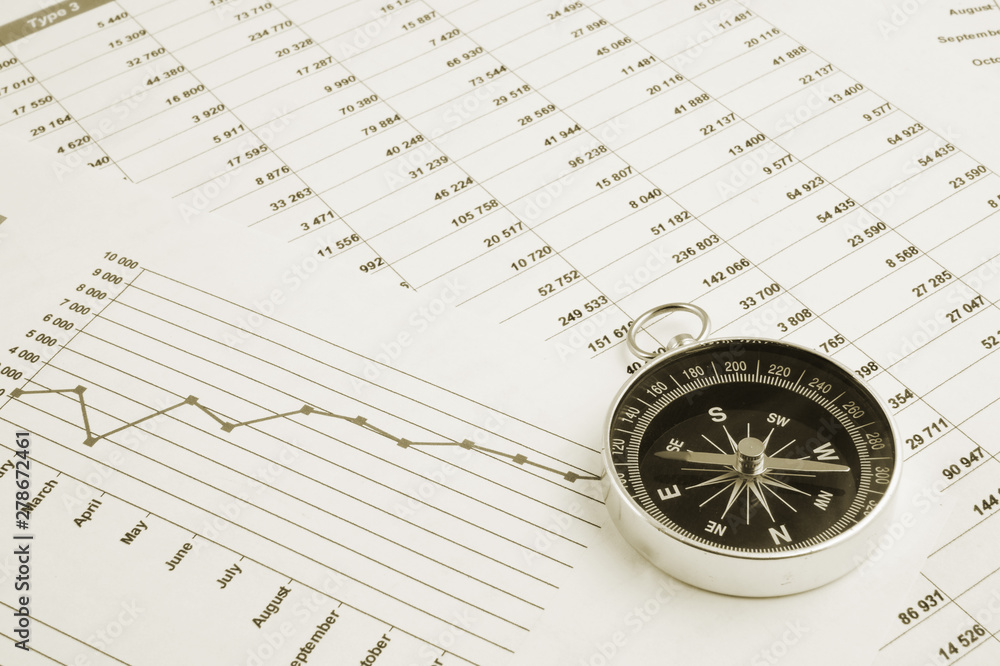 Navigation in financial world, compass on financial charts and graphs Navigation in financial world, compass on financial charts and graphs