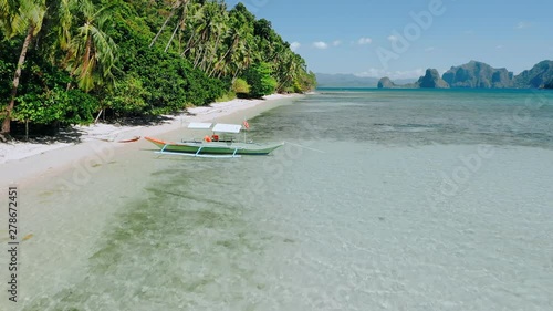 4k Aerial drone flying along exotic cost over banca boat in shallow lagoon water at the low tide. Exploring El Nido, Palawan, Philippines. Summer and travel vacation concept photo