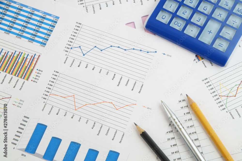 Business concept, calculator, silver pen and pencils on financial charts and graphs Business concept, calculator, silver pen and pencils on financial charts and graphs