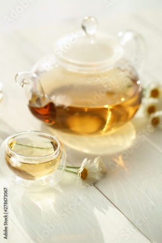 Chamomile tea. natural chamomile tea in a transparent glass teapot and cups, chamomile flowers on a white wooden table.Herbal Green Teas