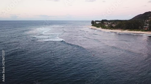 Drone shot flying over surfers enjoying the waves off of the North Shore coast of Oahu, Hawaii. photo