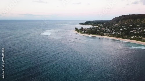 Drone Shot flying along the North Shore coastline of Oahu, Hawaii. Surfers can be seen below in the water enjoying the waves. photo