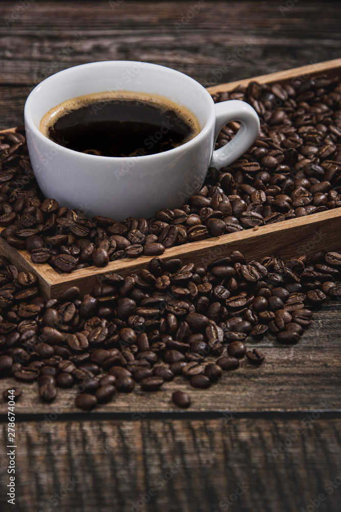 Fototapeta premium cup of coffee with beans on wooden table