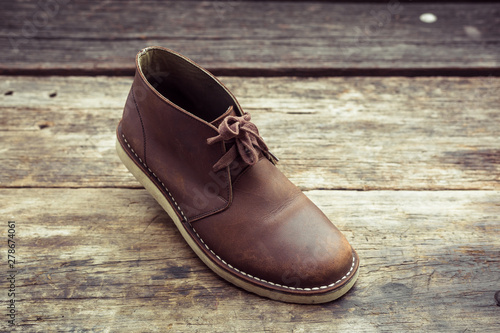 Brown stylish boots on wood background,  retro color