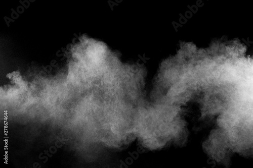 Freeze motion explosion of white dust on a black background. By throwing talcum powder out of hand. Stopping the movement of white powder on dark background.