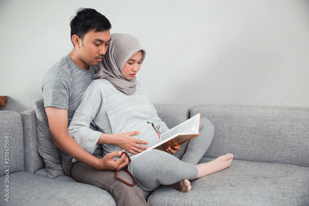 wife and husband learn how to read qoran. muslim family reading holy book of islam wife and husband learn how to read qoran. muslim family reading holy book of islam