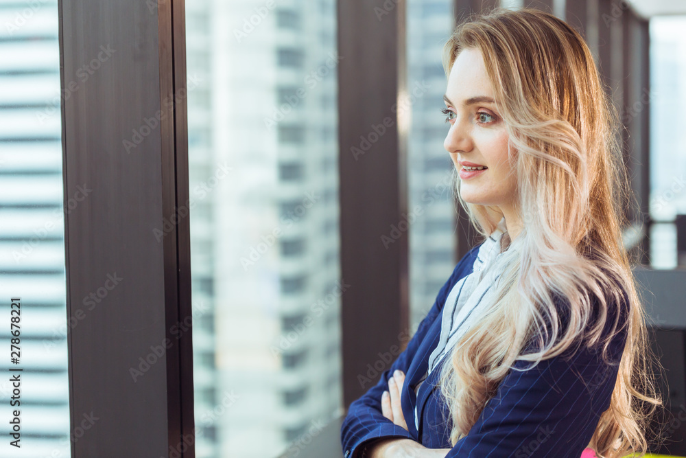 Caucasian russian business woman standing looking out of office windows smiling good mood Caucasian russian business woman standing looking out of office windows smiling good mood