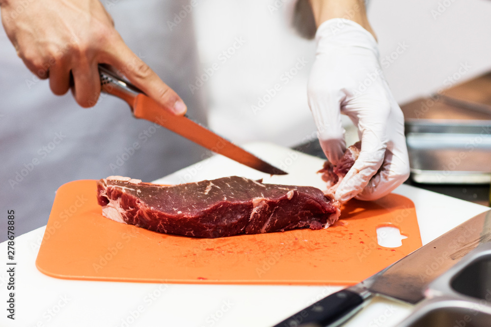 Chef cutting fresh raw meat with knife in the kitchen, Chef cutting beef on a board