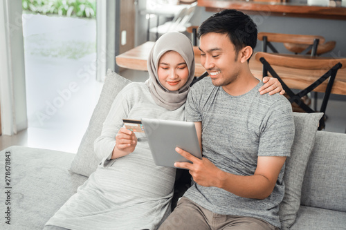 asian muslim couple buy and do payment using credit card while online shopping on market place