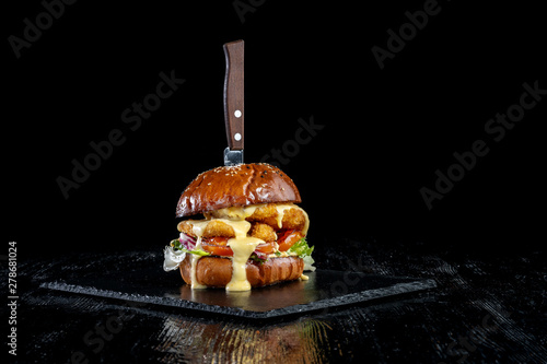 Chicken nuggets burger with fresh onions, tomato and cheese. White bun with sesame.