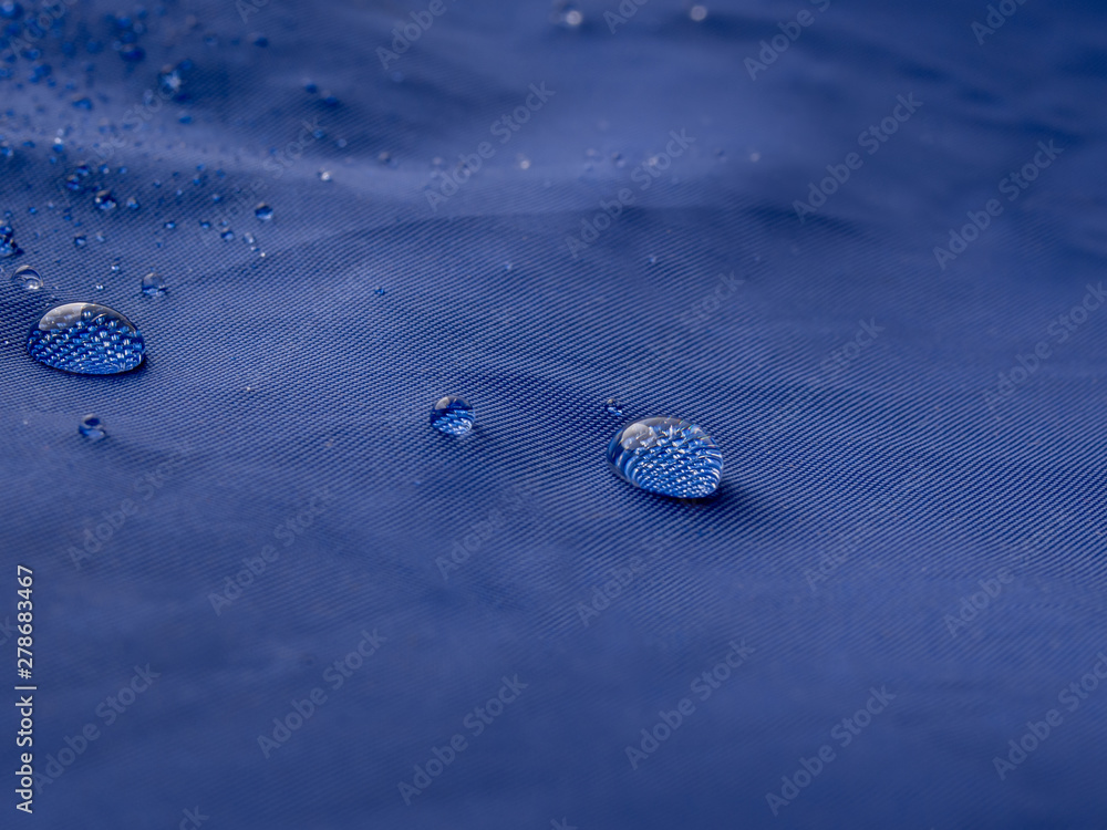 Rain water droplets on blue fiber waterproof fabric. Blue background. Rain water droplets on blue fiber waterproof fabric. Blue background.