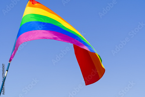 Gay rainbow flag waving in the wind in a clear blue sky