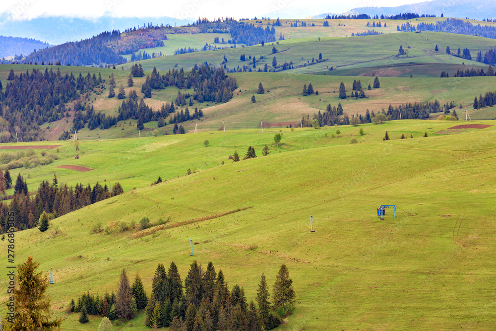 Landscape of the spring Carpathian mountains with blue masts of a mountain cable lift leading to the top of the mountain.
