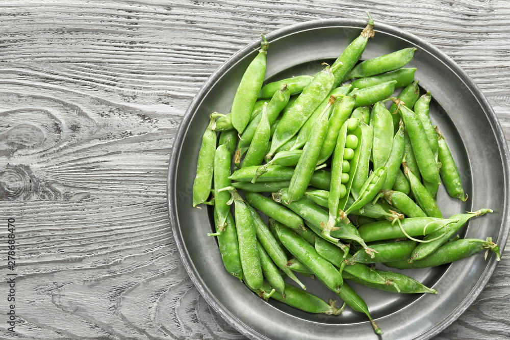 Plate with tasty fresh peas on wooden table Plate with tasty fresh peas on wooden table