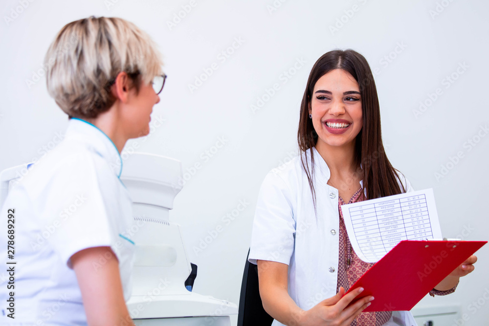 female ophthalmologist showing patient's data to a clipboard, working in an optical store. Healthcare and medicine concept female ophthalmologist showing patient's data to a clipboard, working in an optical store. Healthcare and medicine concept